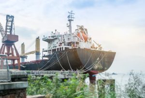 Large cargo ship docked in harbor, with containers stacked on deck