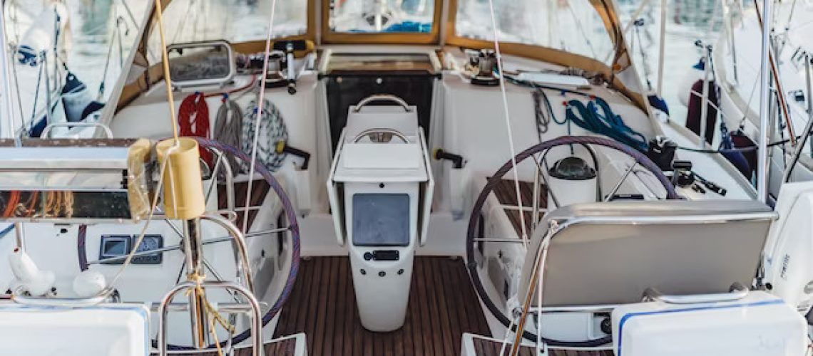 A sailboat cockpit docked in a marina. The cockpit is open and spacious, with a comfortable seating area and a steering wheel.