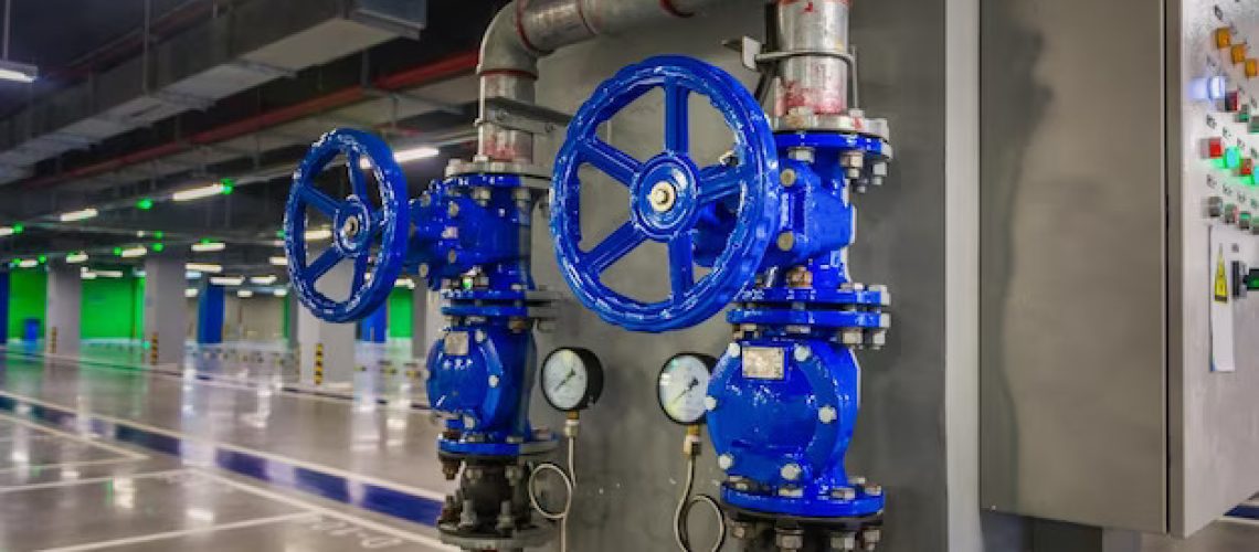 A photo of two blue valves and a control panel in industrial area